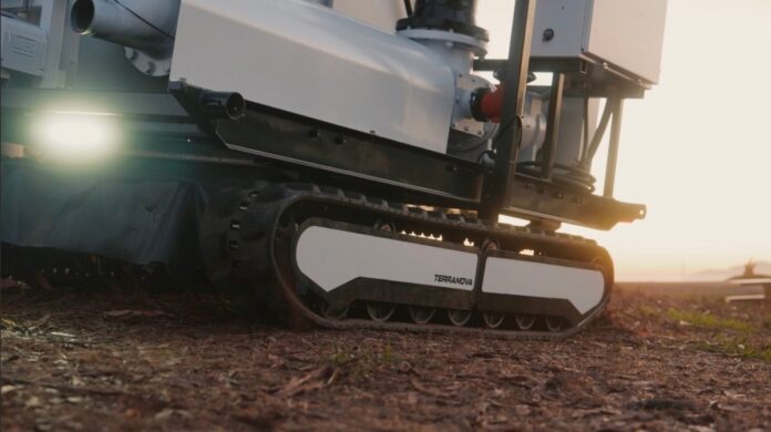 An autonomous, tracked robot sits on a dirt patch.